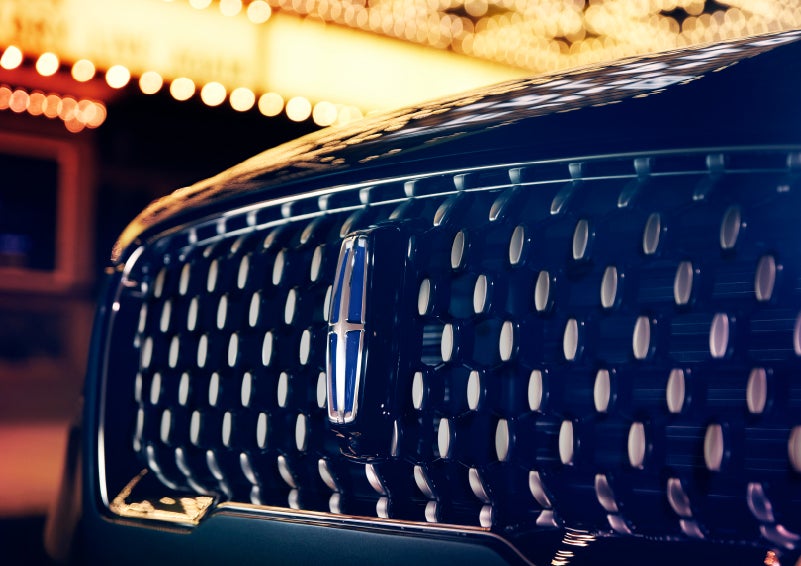 The Corsair Grand Touring grille shows floating chrome ovals that catch the glowing light of a theater marquee and frame the distinctive Lincoln Star | Klaben Lincoln of Warren in Warren OH