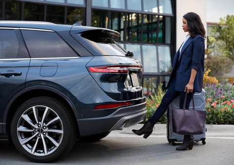 A woman with luggage and a bag opens the available hands-free liftgate by kicking her foot under the bumper | Klaben Lincoln of Warren in Warren OH