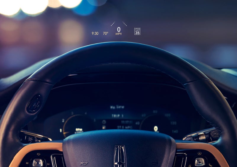 The available head-up display projects data on the windshield above the steering wheel inside a 2022 Lincoln Corsair as the driver navigates the city at night | Klaben Lincoln of Warren in Warren OH