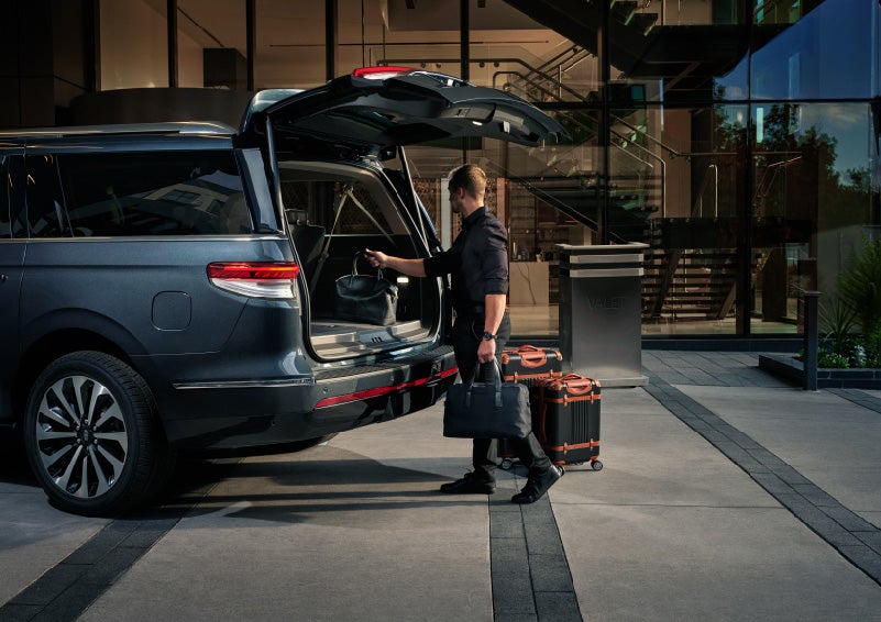 A valet is unloading luggage from the rear cargo area of a 2022 Lincoln Navigator SUV | Klaben Lincoln of Warren in Warren OH