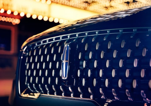 The Corsair Grand Touring grille shows floating chrome ovals that catch the glowing light of a theater marquee and frame the distinctive Lincoln Star | Klaben Lincoln of Warren in Warren OH