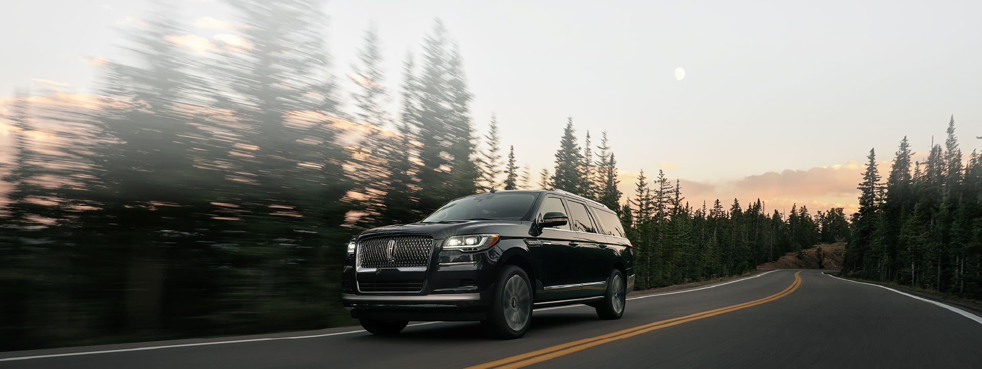 A 2022 Lincoln Navigator SUV is driving along a mountain road with grounding power