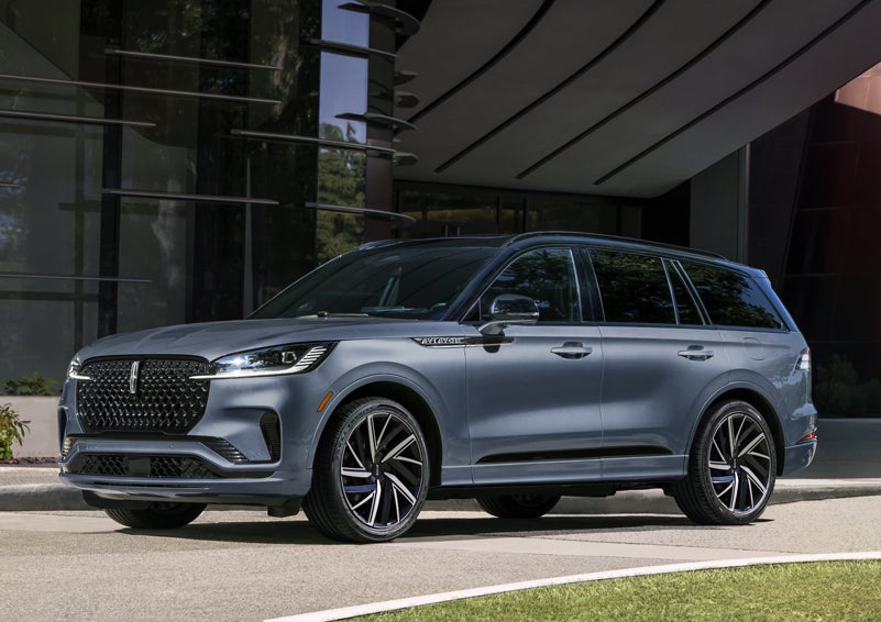 A gray 2025 Lincoln Aviator® SUV is parked outside a modern building showcasing the driver’s side of the vehicle. | Klaben Lincoln of Warren in Warren OH