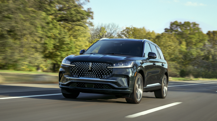 A 2025 Lincoln Black Label Aviator® SUV is being driven down a road lined with trees. | Klaben Lincoln of Warren in Warren OH