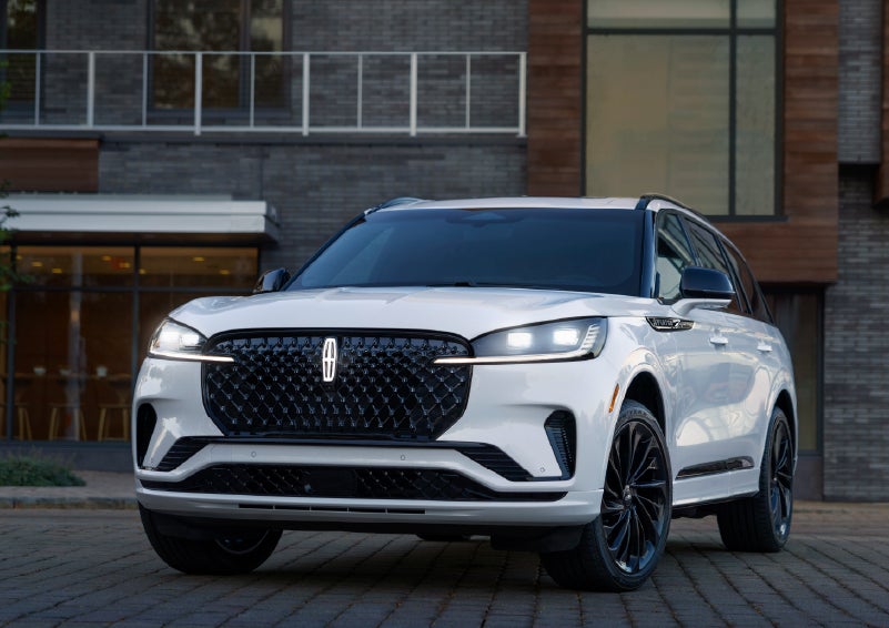 A 2026 Lincoln Aviator® Reserve model is shown with the available Jet Appearance Package parked near a restaurant. | Klaben Lincoln of Warren in Warren OH