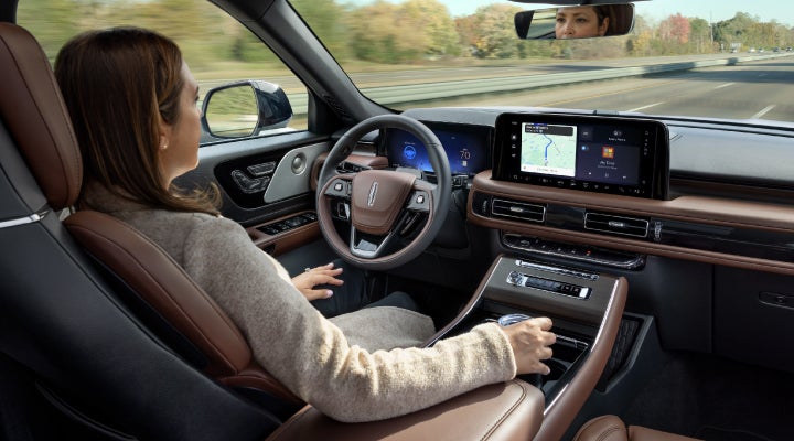 A 2026 Lincoln Aviator® SUV is being driven hands-free on a highway near a forest | Klaben Lincoln of Warren in Warren OH