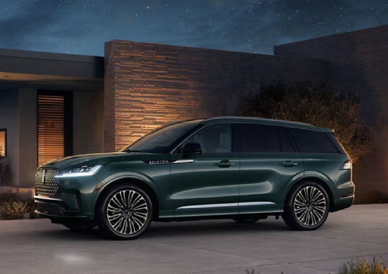 A green 2027 Lincoln Aviator® SUV is parked outside a contemporary home. | Klaben Lincoln of Warren in Warren OH
