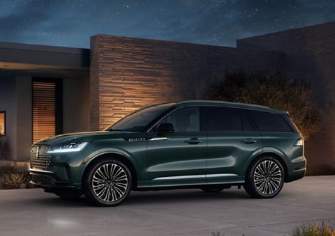 A green 2027 Lincoln Aviator® SUV is parked outside a contemporary home. | Klaben Lincoln of Warren in Warren OH