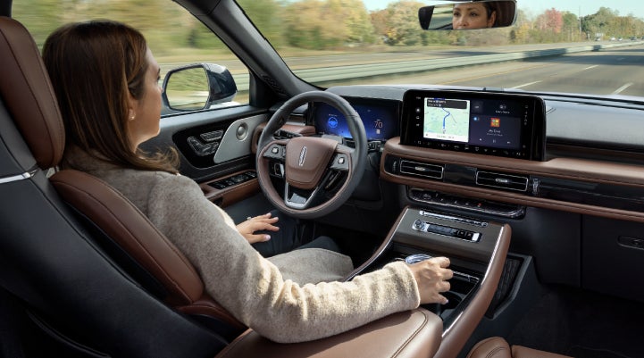 A 2027 Lincoln Aviator® SUV is being driven hands-free on a highway lined with trees. | Klaben Lincoln of Warren in Warren OH