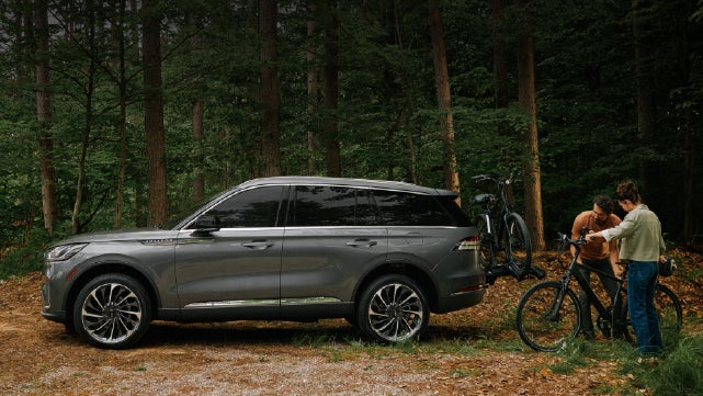 A father and son load e-bikes on a bike rack attached to a 2027 Lincoln Aviator® SUV. | Klaben Lincoln of Warren in Warren OH