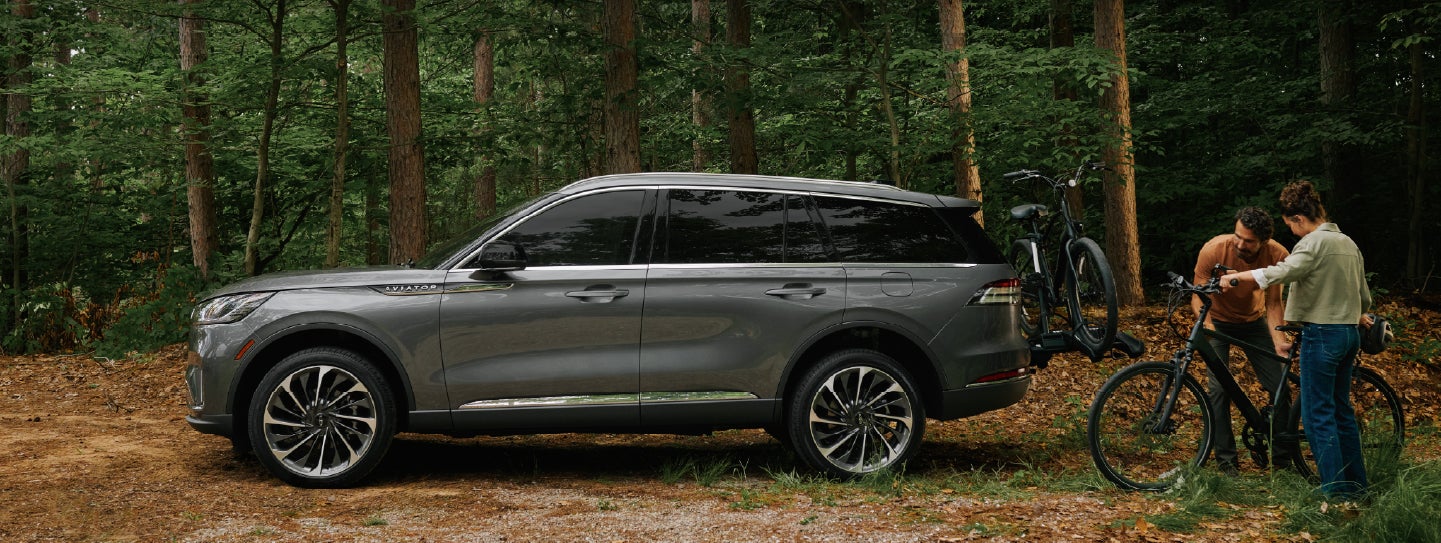 A father and son load e-bikes on a bike rack attached to a 2027 Lincoln Aviator® SUV. | Klaben Lincoln of Warren in Warren OH
